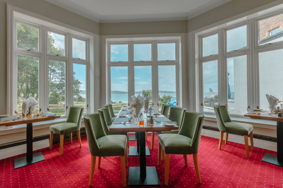 Restaurant tables in a bay window looking out to sea
